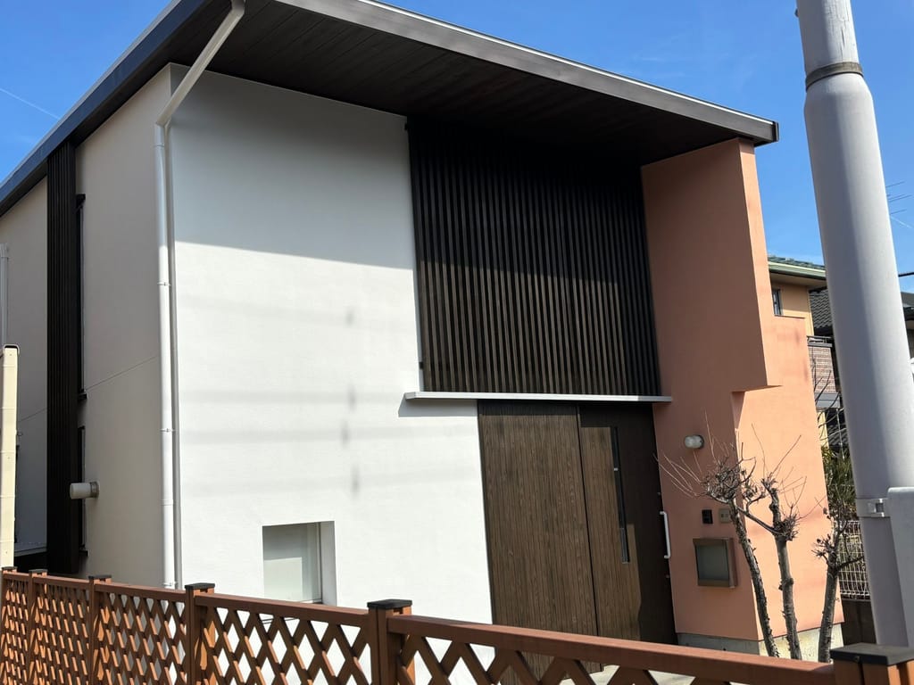 H様邸 施工後。白い外壁とテラコッタ色の壁、木製の格子とドア